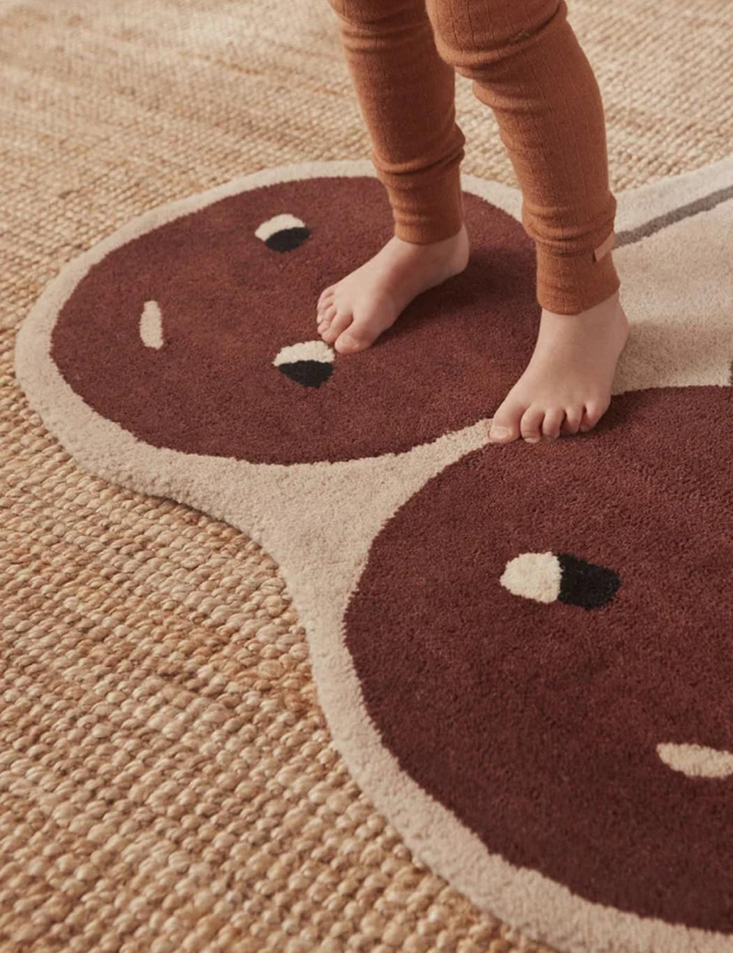 Children's legs standing on a rug with a Cherry design.