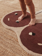 Children's legs standing on a rug with a Cherry design.